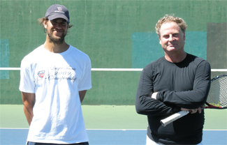 A couple of men stand near each other holding tennis rackets Description automatically generated with medium confidence